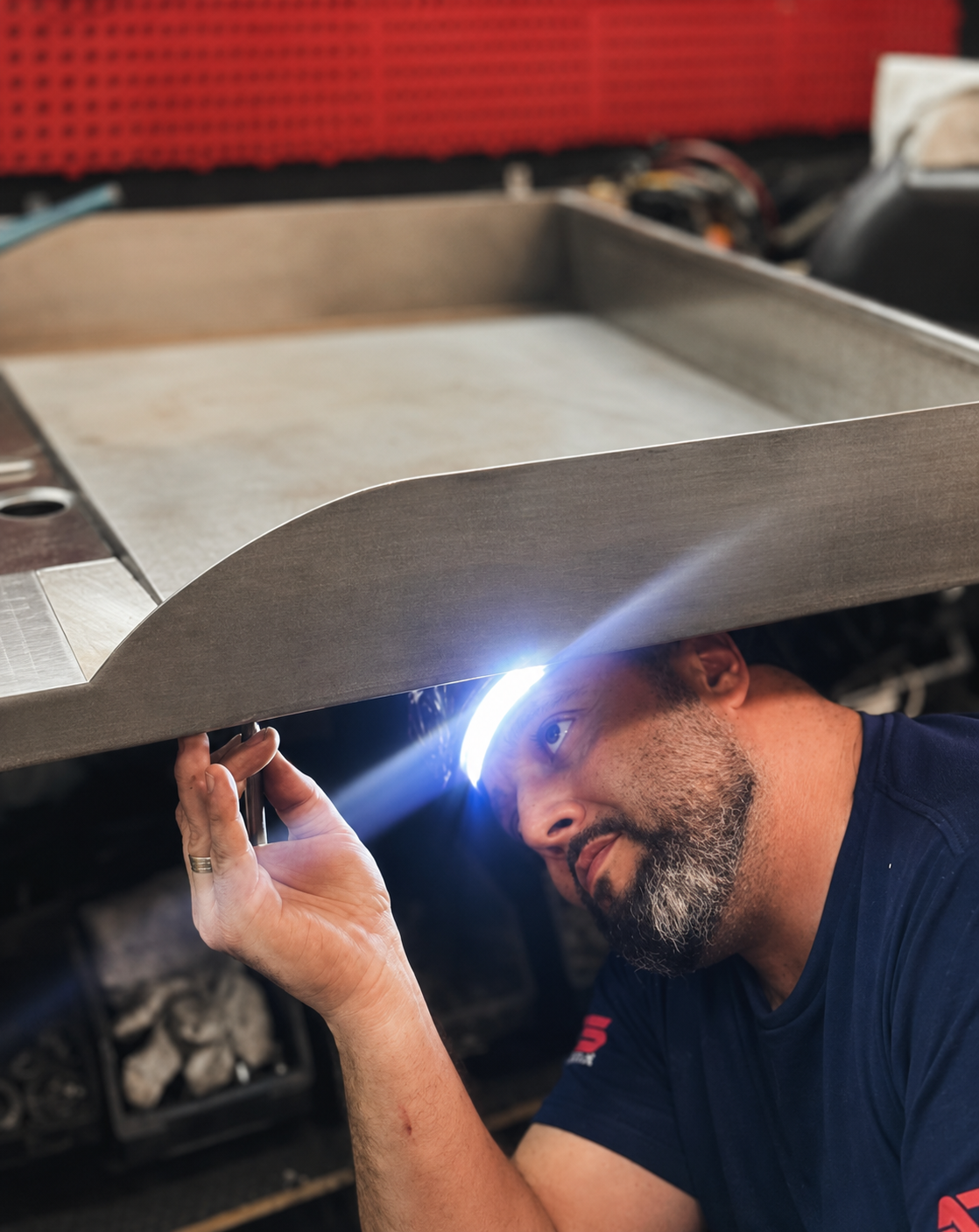Técnico A-Tech inspecionando equipamento de cozinha industrial com lanterna